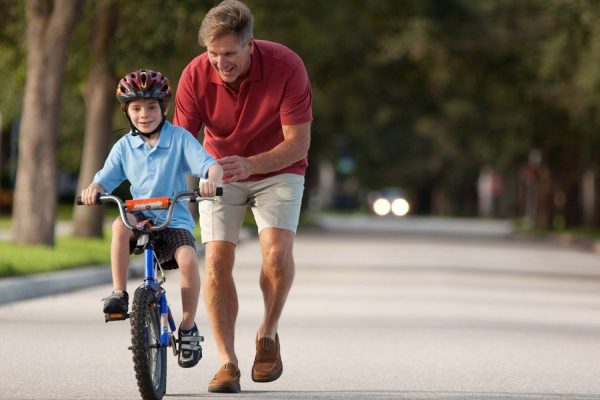 Father teaching son how to ride a bike